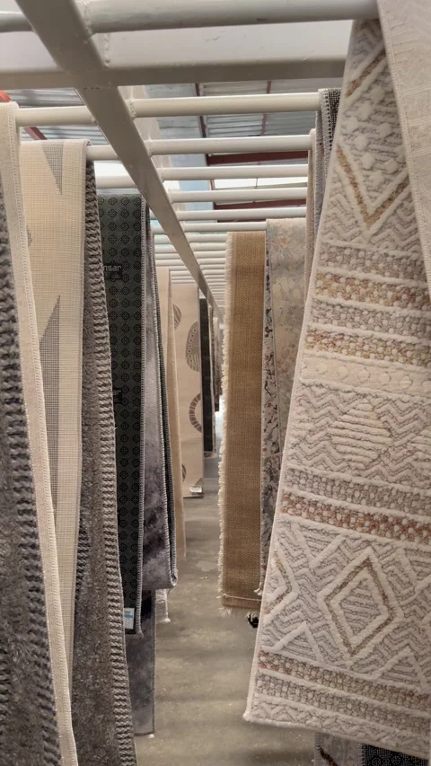 Patterned rugs hanging in a narrow warehouse aisle Stock Footage 337876740
