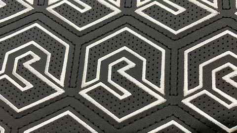 Patterned stitching, embroidery and perforations on black leather Stock Photos