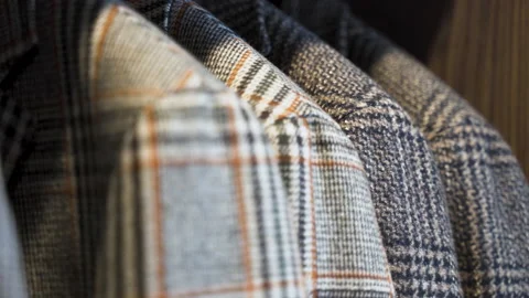 Patterned tailored tweed jackets hanging in wooden wardrobe, close up. Stock Footage 205451019