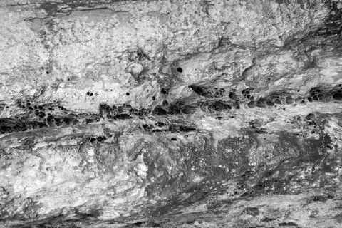 Patterns and textures of a rock wall with holes, black and white Stock Photos