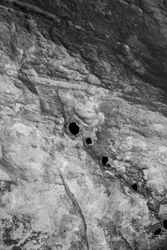 Patterns and textures of a rock wall with holes, black and white Stock Photos