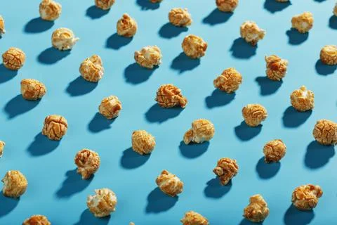 Patterns of caramel popcorn on a blue background in the form of a pattern. Stock Photos