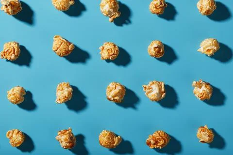 Patterns of caramel popcorn on a blue background in the form of a pattern. Stock Photos