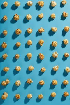 Patterns of caramel popcorn on a blue background in the form of a pattern. Stock Photos