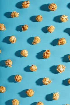 Patterns of caramel popcorn on a blue background in the form of a pattern. Stock Photos