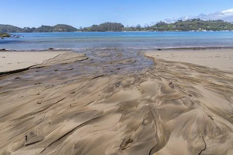 Patterns in created by water from small stream washing across beach to waters Stock Photos