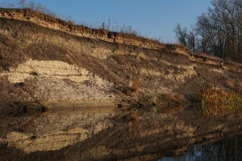 Patterns on the cut of a steep slope of a clay river bank Stock Photos