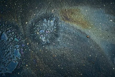 Patterns on the Ground After Rain Show Colors From Oil in a City Street During a Stock Photos