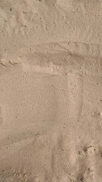 Patterns in the sand reveal unique shapes and marks from beachgoers during .. Stock Photos