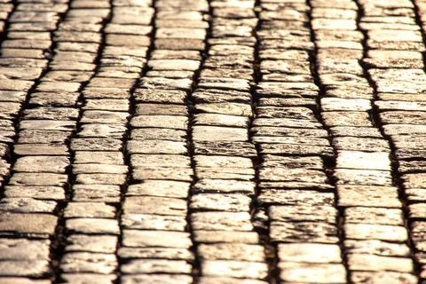 Patterns of sunlight illuminating cobblestone pathway in an urban setting d.. Stock Photos
