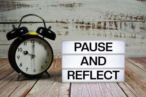 Pause and Reflect text on light box with alarm clock on wooden background Stock Photos