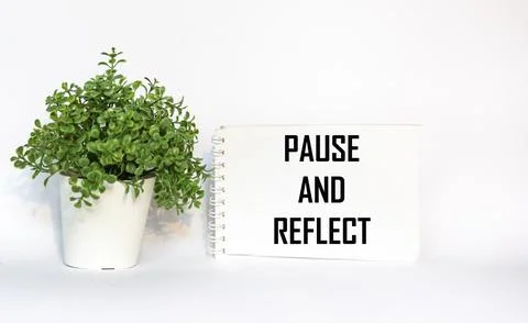 Pause and reflect. Words on a notebook , white background with a flower Stock Photos