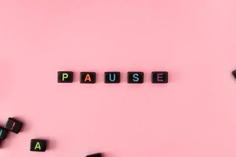 Pause button concept. Black beads on pink background making word Stock Photos