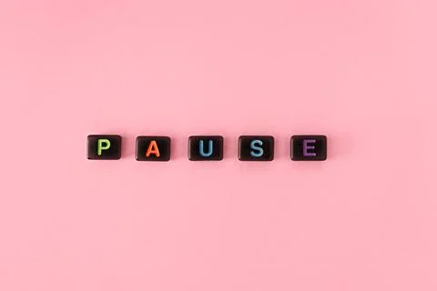 Pause button concept. Black beads on pink background making word Stock Photos