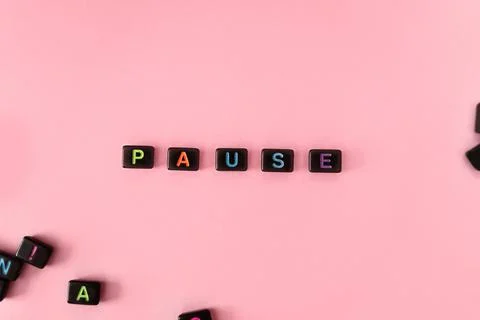 Pause button concept. Black beads on pink background making word Stock Photos