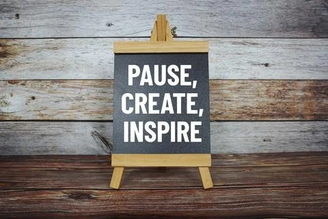 Pause, Create, Inspire text on easel blackboard on wooden background Stock Photos