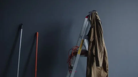 Pause in Domestic Routine: Cleaning Tools and Jacket Against a Grey Backdrop Stock Footage 259884377