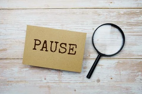 Pause text message and magnifying glass with space copy on wooden background Stock Photos