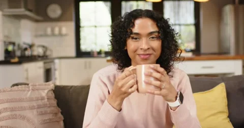 Pausing gaze, non-binary adult lifting mug toward lips while savoring hot drink Stock Footage 337159593