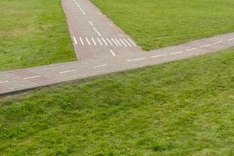 Paved concrete paths in a park among a trimmed green lawn Stock Photos