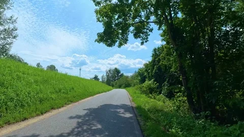 Paved country path winding through green hillside and trees. Bicycle POV Stock Footage 341974031