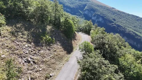 A paved mountain road winds between steep rocky 動画素材 346289825