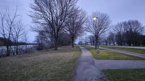Paved Park Pathway Along Riverfront Under Dusk Winter Sky Stock Photos