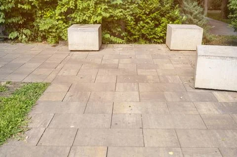 Paved park square with decorative stone cubes and lush green trees. Modern Stock Photos