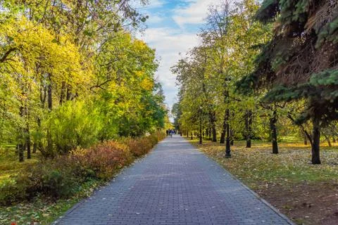 A paved path with gray and red paving slabs with a group of people and yellow Stock Photos