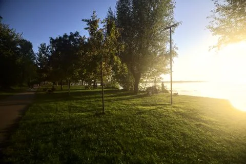 Paved path in a park by the lakeshore at sunset Stock Photos