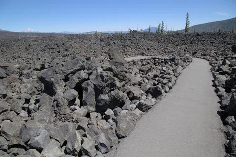 A paved path winds through the rugged black volcanic lava field in Oregon u.. Stock-Fotos