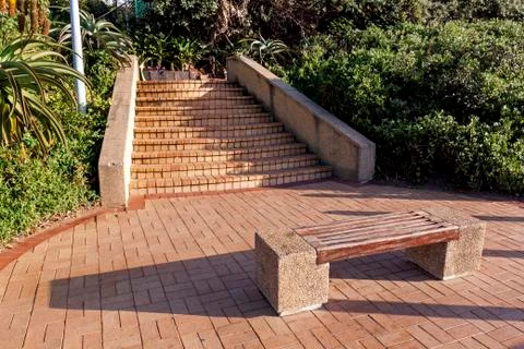Paved Pathway and Steps with Empty Wooden Bench Stock Photos