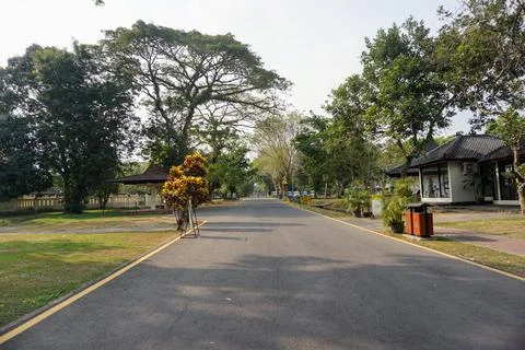 Paved road surrounded by lush trees near the exit of Prambanan Temple cultural Stock Photos