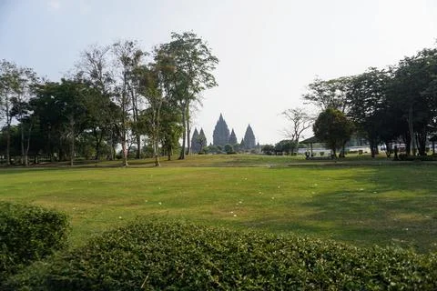 Paved road surrounded by lush trees near the exit of Prambanan Temple cultural Stock Photos