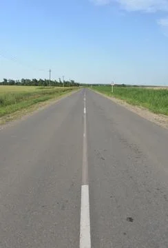 Paved road through green fields and hills in summer Stock Photos