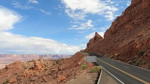 A paved road winds through a red rock canyon landscape under a blue sky with -40 Stock-Footage 346411290