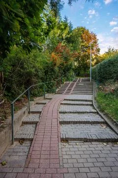 Paved stone staircase with a red brick bicycle ramp leading up through a gr.. Stock Photos