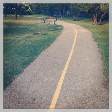 Paved trail and isolated bench Stock Photos