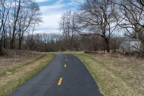A paved walking path at a local Minnesota park surrounded by grass and trees. Stock Photos