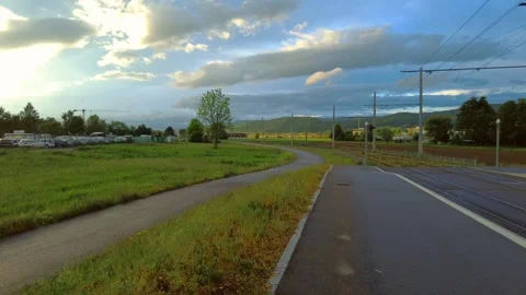 Paved walking path next to an asphalt road with fields and a railway line on the Stock Footage 334865483
