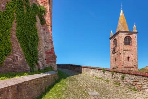 Paved walkway between brick wall and bell tower. Stock Photos
