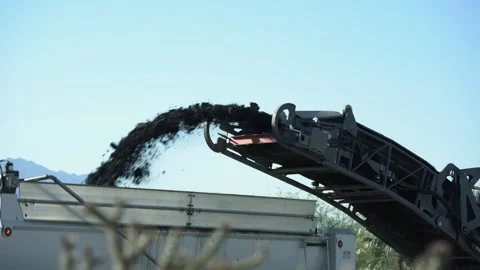 A pavement milling conveyor spewing chunks of asphalt during road construction Stock Footage 152735568