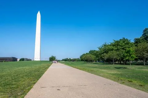 Pavement path through trees green grass  leading to Washington Monument Stock Photos