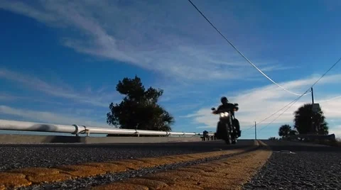 Pavement view shot of motorcycle coming over bridge Stock Footage 45289315