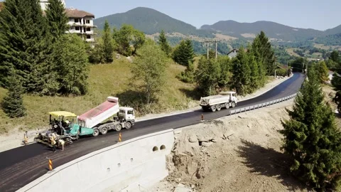 Paver and Dump Trucks Laying Asphalt on New Mountain Road Bridge Section Stock Footage 322195570