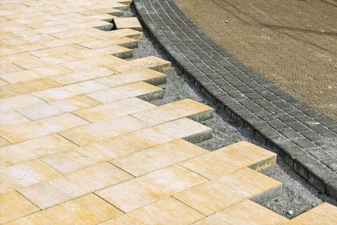 Paver installation reveals methodical step joint with curved border, gravel.. 스톡 사진