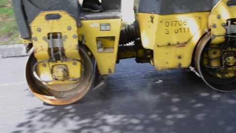 Paver, paving machine. Yellow old asphalt paving machine rolls asphalt on street Stock Footage 241433591