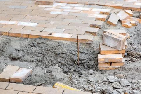 Paving of a new sidewalk from rectangular stone tiles according to marks. Stock Photos