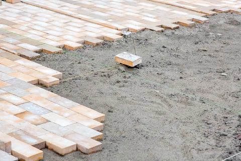 Paving of a new sidewalk from rectangular stone tiles. Stock Photos