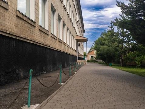 Paving path with green pillars in front of a brick building Stock Photos